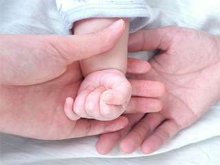 赤ちゃんの小さな手を握るパパとママ